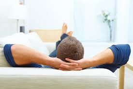Picture 17 of a man reclining on a sofa with his hands behind his head